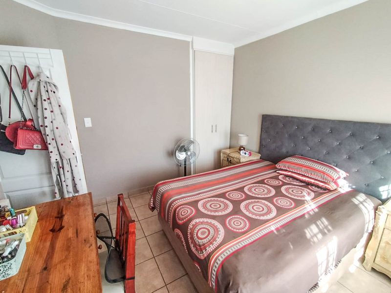 A functional bedroom featuring tiled flooring, neutral wall tones, and a built-in wardrobe, offering a practical space for rest.