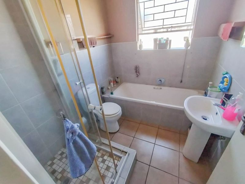 A functional bathroom featuring a separate shower enclosure, bathtub, pedestal basin, and toilet with tiled finishes throughout.