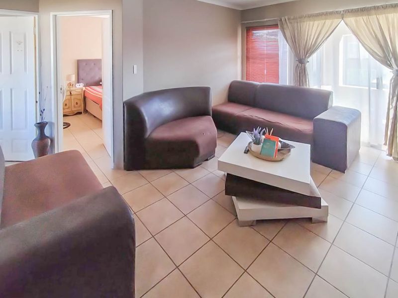 A living room featuring ceramic floor tiles, coved ceilings, and a sliding glass door providing access to the exterior.