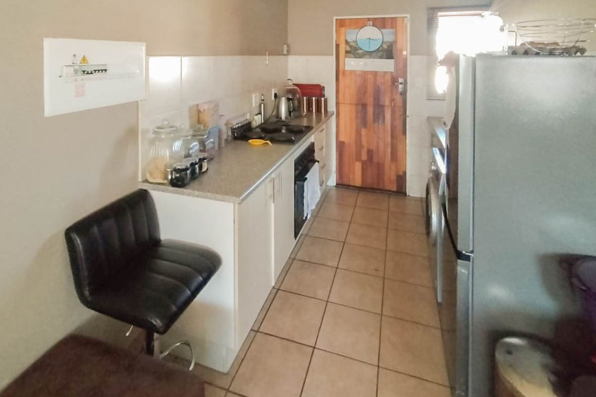 A functional galley-style kitchen featuring tiled flooring, built-in cabinetry, a hob, and an oven, with a neutral color palette.