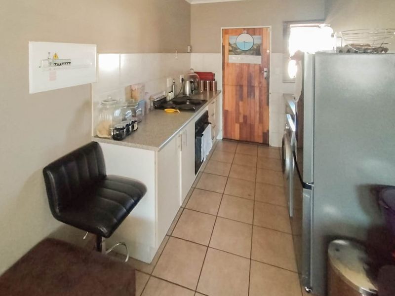 A functional galley-style kitchen featuring tiled flooring, built-in cabinetry, a hob, and an oven, with a neutral color palette.