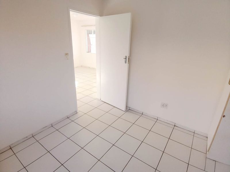 An empty bedroom featuring white walls and neutral ceramic floor tiles, providing a blank canvas for personalization.