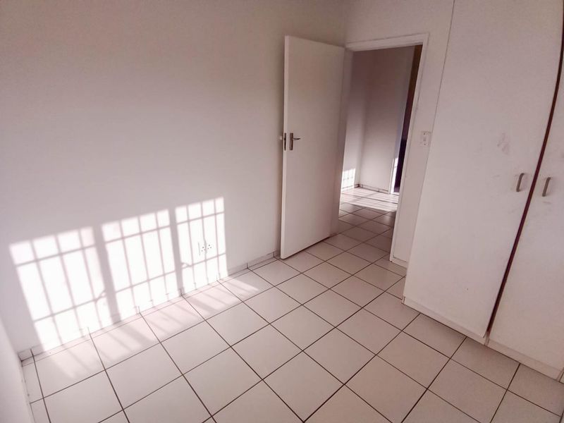 An empty bedroom featuring neutral tiled flooring and built-in cupboards, offering a clean, blank canvas for personalization.