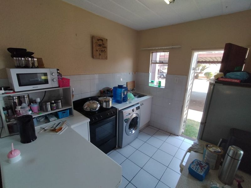 A functional kitchen featuring tiled flooring, a built-in stove and oven, tiled splashbacks, and direct access to the exterior.