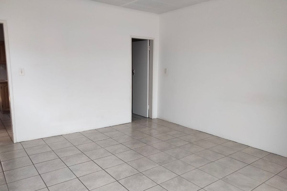 A bright, empty living area featuring neutral ceramic floor tiles and clean white walls, providing a versatile blank canvas for interior design.