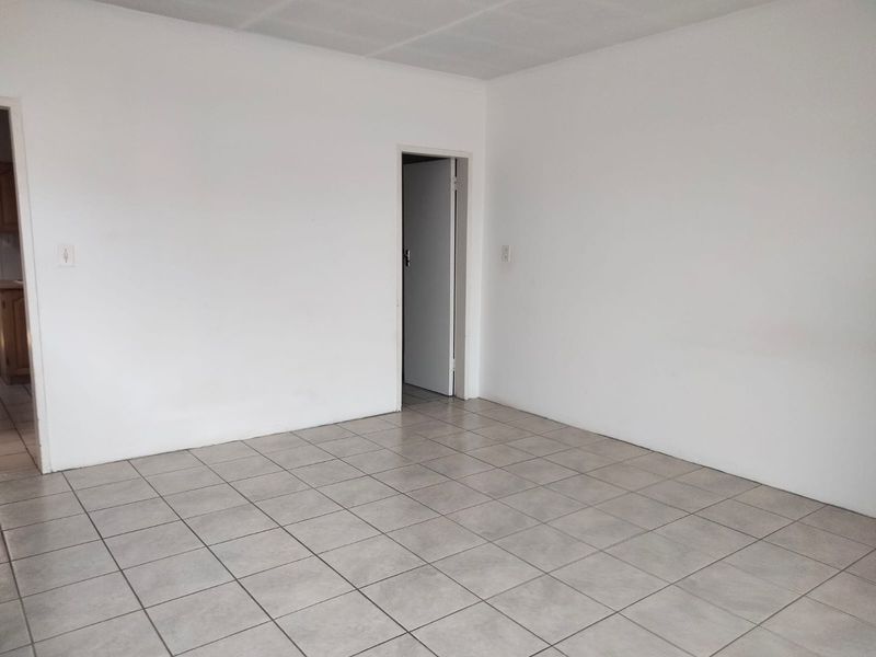 A bright, empty living area featuring neutral ceramic floor tiles and clean white walls, providing a versatile blank canvas for interior design.