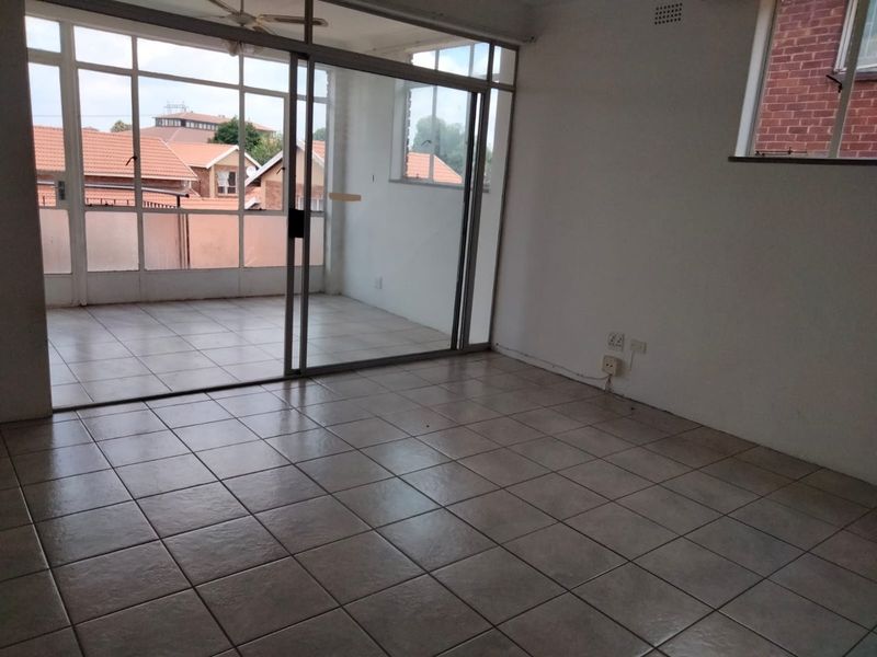 An empty living room featuring tiled flooring and large sliding glass doors that open onto an enclosed patio area.