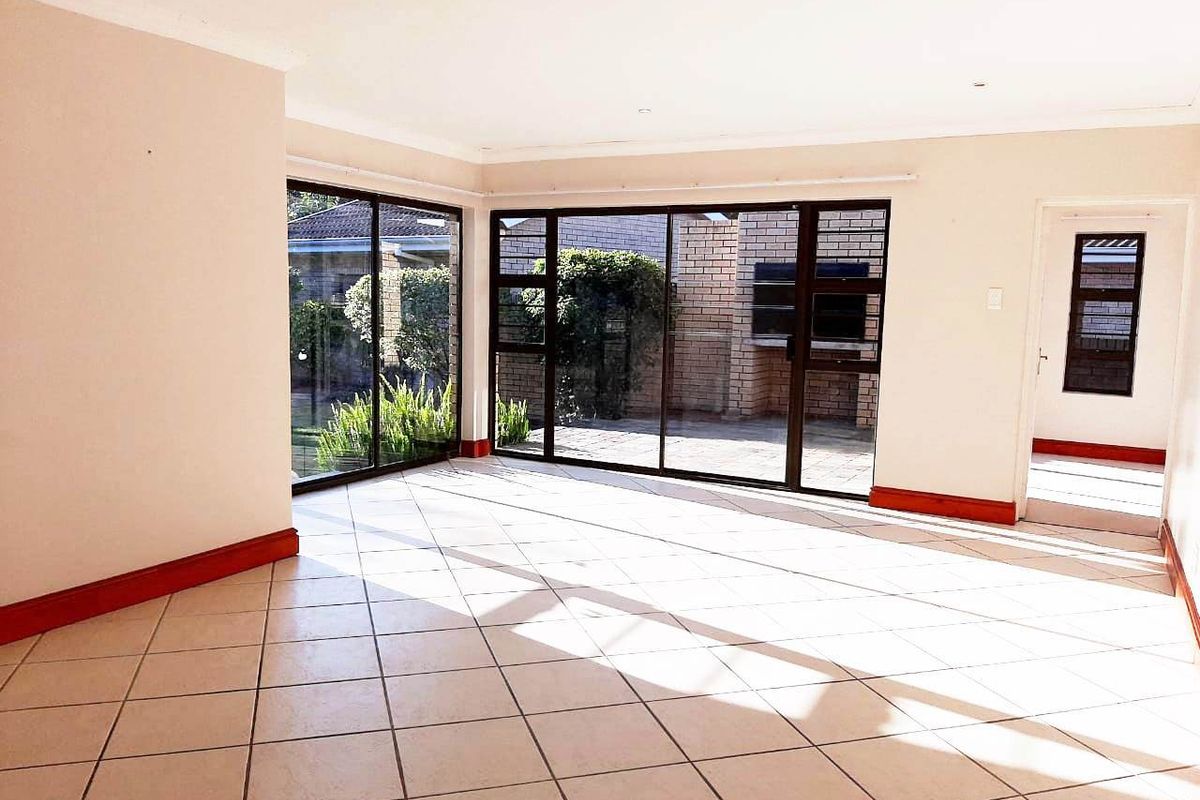 Spacious, light-filled living area featuring neutral tiled flooring, large sliding glass doors providing garden access, and clean, minimalist finishes throughout.