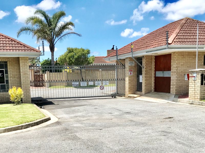 Front entrance view of Weybridge Estate featuring a brick facade, tiled roof, and secure gated access with electric fencing.