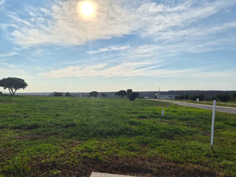 A view of a vacant residential plot of land with road access, suitable for new construction.