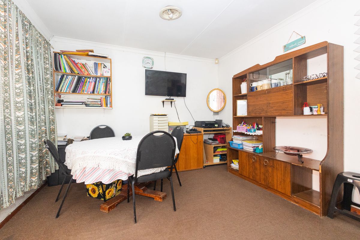 A functional living area featuring carpeted flooring and standard ceiling cornicing, offering a versatile space for dining or relaxation.