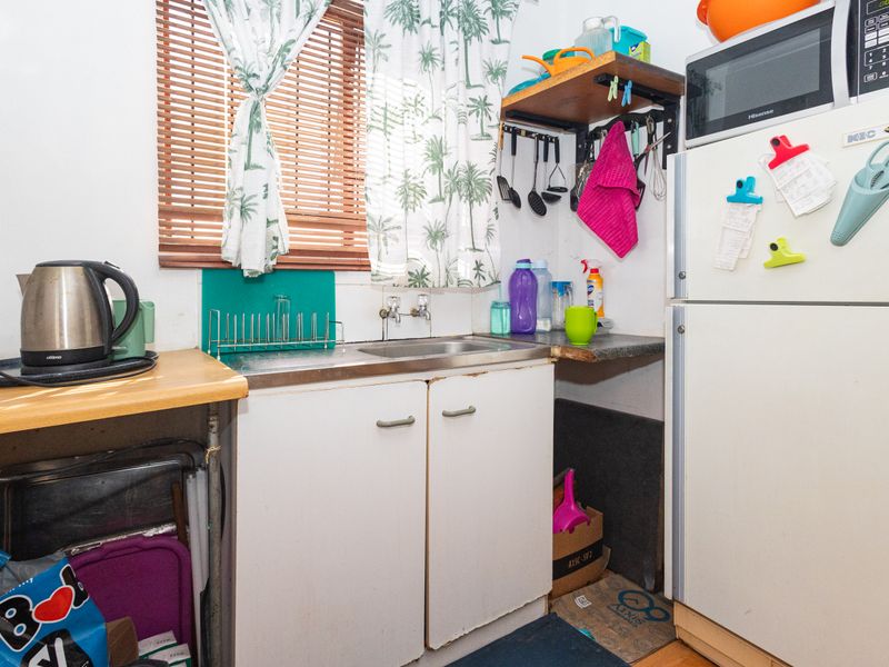 A compact scullery or utility area featuring a stainless steel sink, built-in cabinetry, and laminate countertops, providing functional space for food preparation and cleaning.