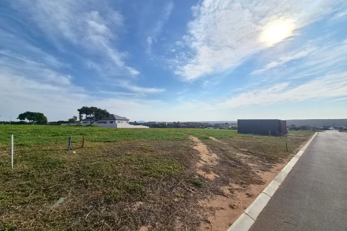A vacant residential plot featuring a paved road frontage, concrete curbing, and utility connection points, ready for development.