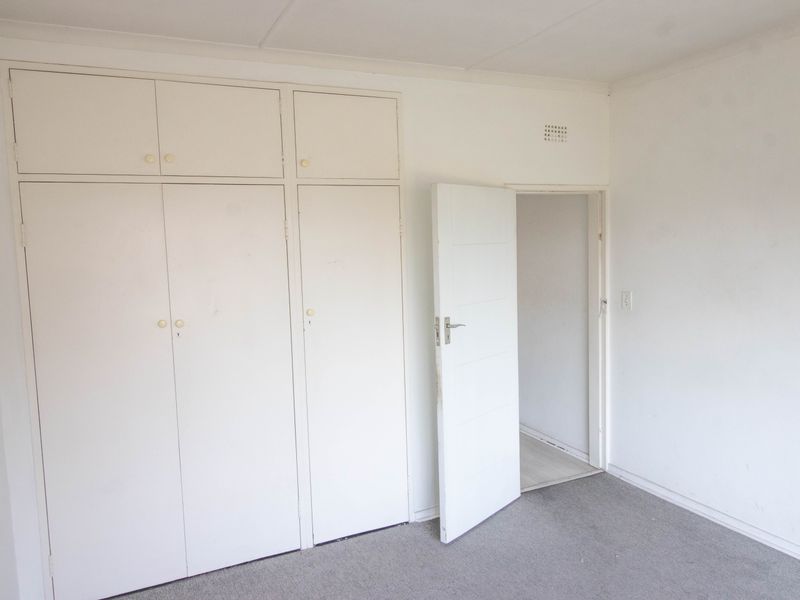 An empty bedroom featuring built-in cupboards and carpeted flooring, presenting a blank canvas for potential renovation or staging.