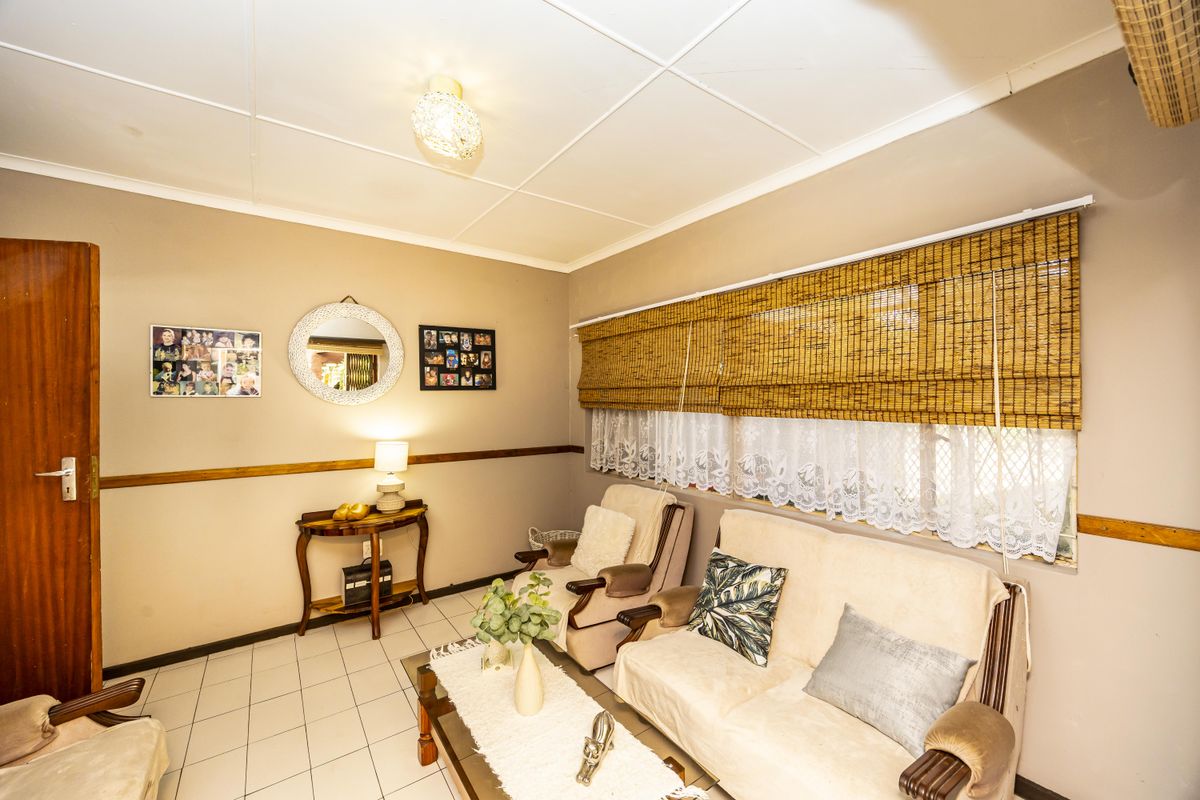 A living room featuring tiled flooring, a timber dado rail, and ceiling tiles, providing a functional and lived-in space.