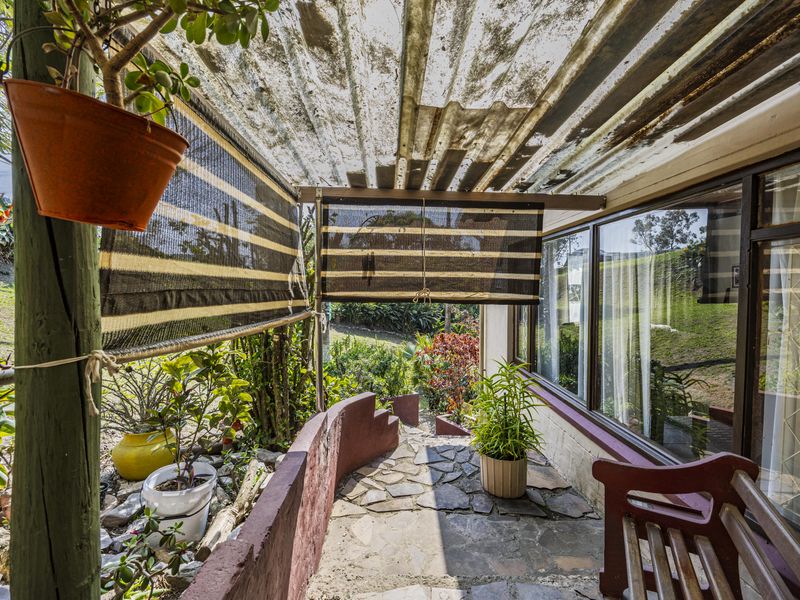Covered outdoor patio area featuring stone paving, a masonry retaining wall, and direct access to the interior through large glass sliding doors.