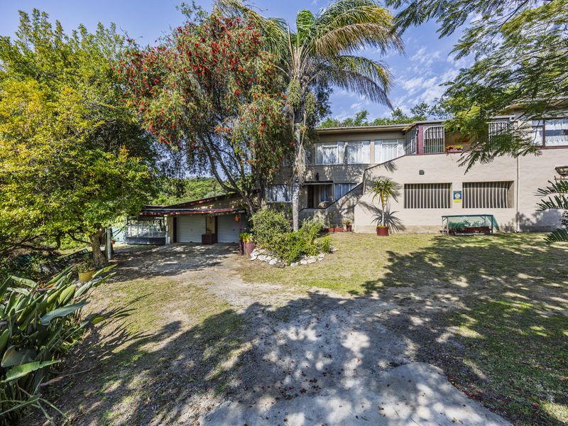 Front view of the property featuring a double garage, security-barred windows, and a mature garden with a paved driveway.