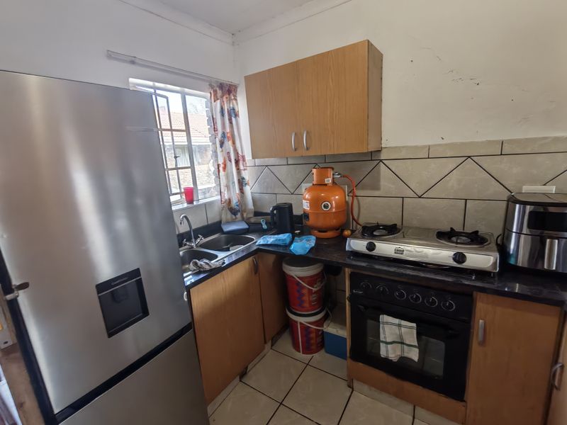 Compact kitchen featuring laminate cabinetry, tiled backsplash, built-in oven, gas hob, and double bowl stainless steel sink.