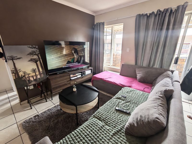 A comfortable living room featuring tiled flooring and natural light from a window, providing a functional space for relaxation.