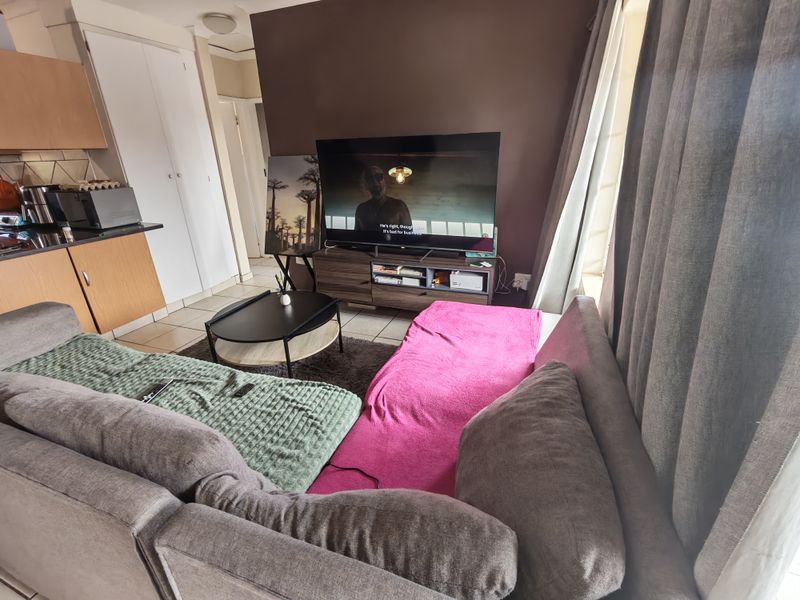 Open-plan living area featuring tiled flooring, integrated kitchen cabinetry, and direct access to a balcony through a sliding door.
