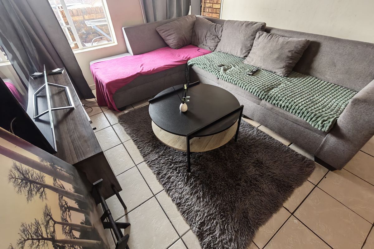 A living room area featuring tiled flooring and a large window, providing natural light to the space.