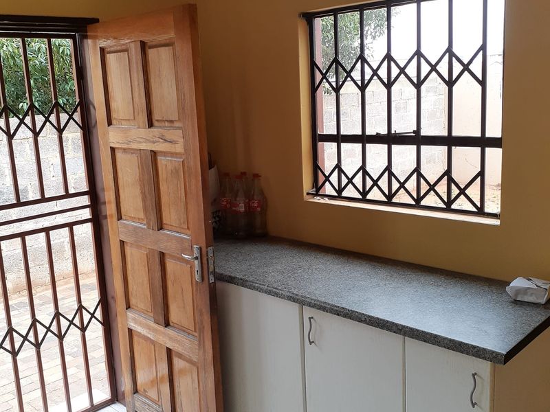 A functional kitchen area featuring built-in white cabinetry, granite countertops, and secure window and door access.