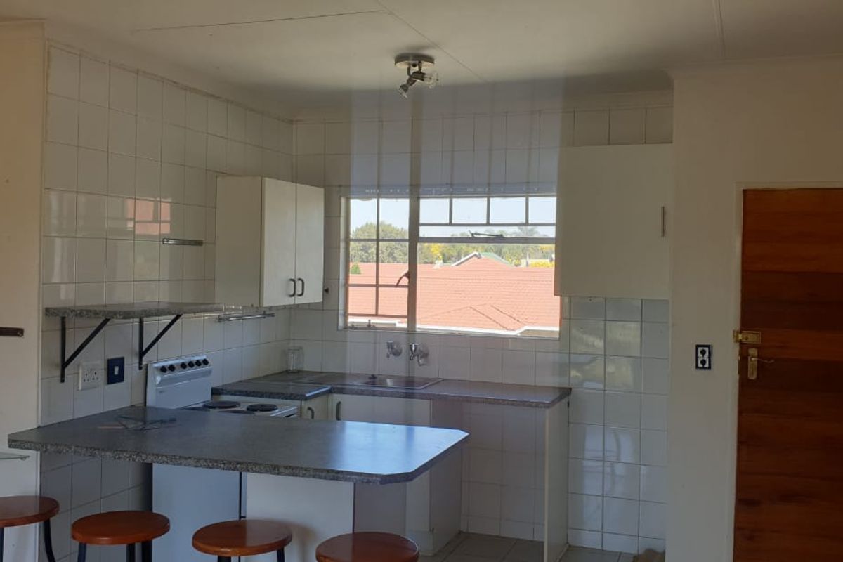 A dated kitchen featuring built-in cabinetry, laminate countertops, a tiled backsplash, and a freestanding stove, offering potential for modernization.