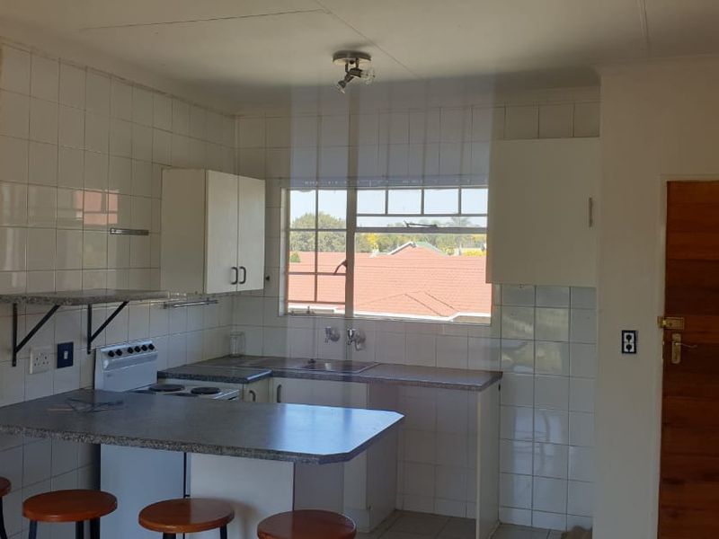 A dated kitchen featuring built-in cabinetry, laminate countertops, a tiled backsplash, and a freestanding stove, offering potential for modernization.