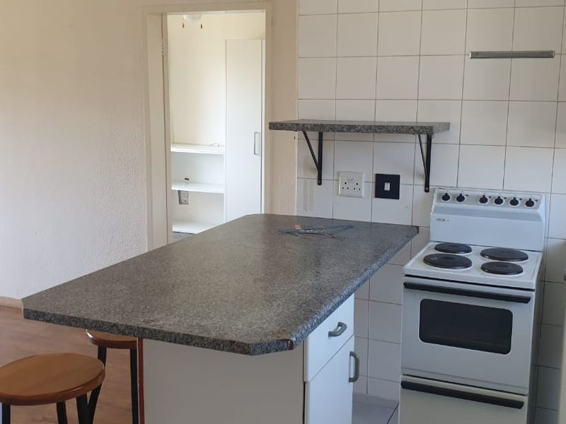 A functional kitchen featuring a breakfast bar, tiled backsplash, and freestanding stove, offering a practical layout with potential for modern updates.