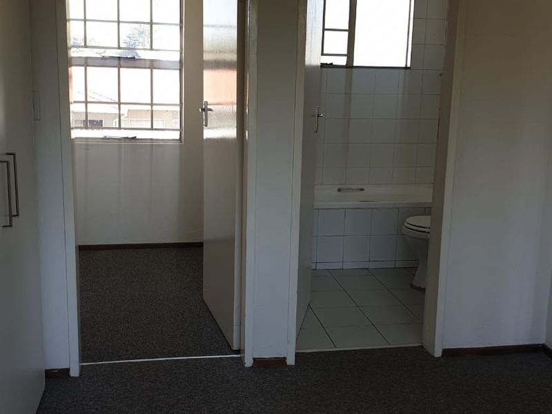 An empty bedroom featuring built-in cupboards and an attached en-suite bathroom with a bathtub.
