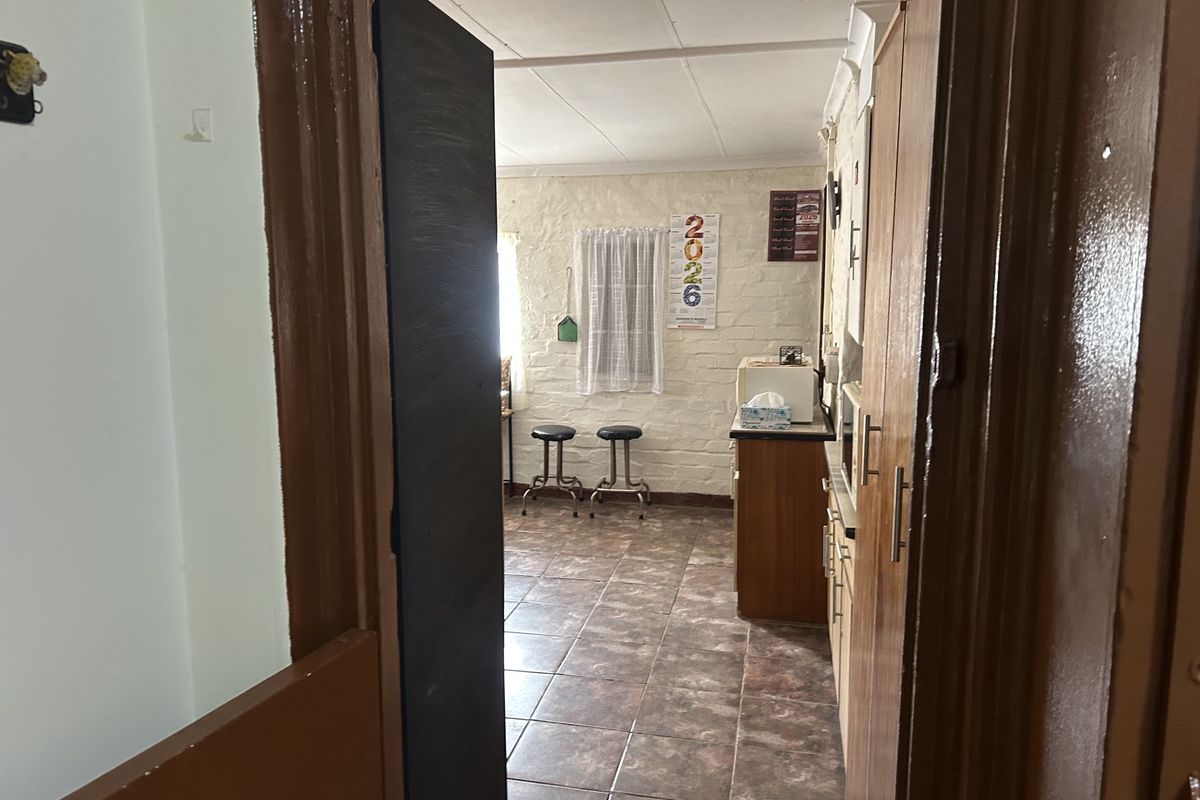 A functional kitchen space featuring tiled flooring, built-in cabinetry, and an exposed brick wall, offering potential for a modern renovation.