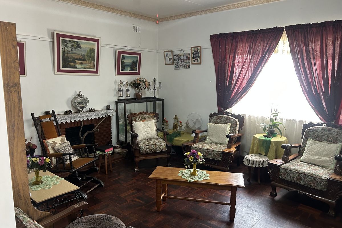 A traditional living room featuring a brick fireplace, classic parquet flooring, and decorative ceiling cornices, offering a warm and character-filled space.