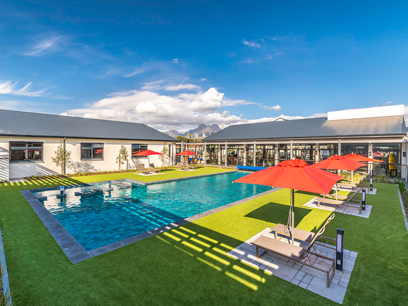 A well-maintained outdoor pool area featuring a swimming pool, artificial turf, and paved deck, set within a modern apartment complex.