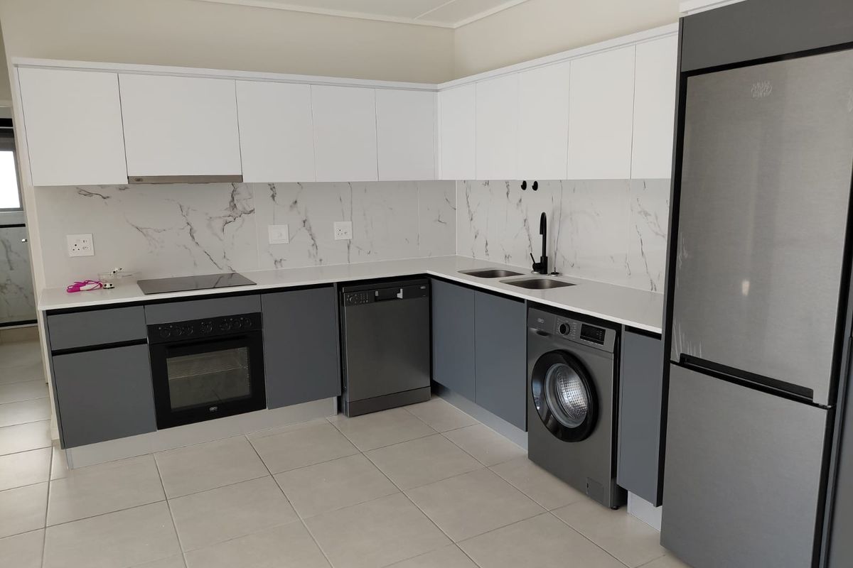 Modern kitchen featuring sleek two-tone cabinetry, marble-look splashback, integrated oven, hob, and extractor fan with tiled flooring.