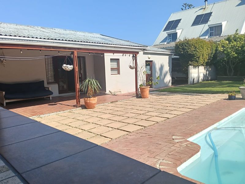 Outdoor pool area featuring a covered patio with timber pergola, brick and concrete paving, and a swimming pool in a private backyard setting.