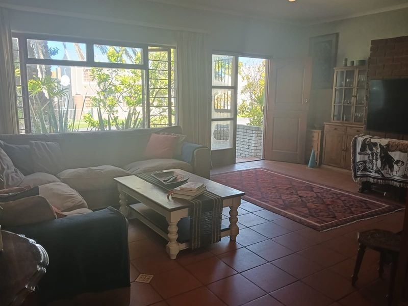 Spacious living room featuring terracotta floor tiles, a brick fireplace, and large windows providing natural light and access to the outdoor area.