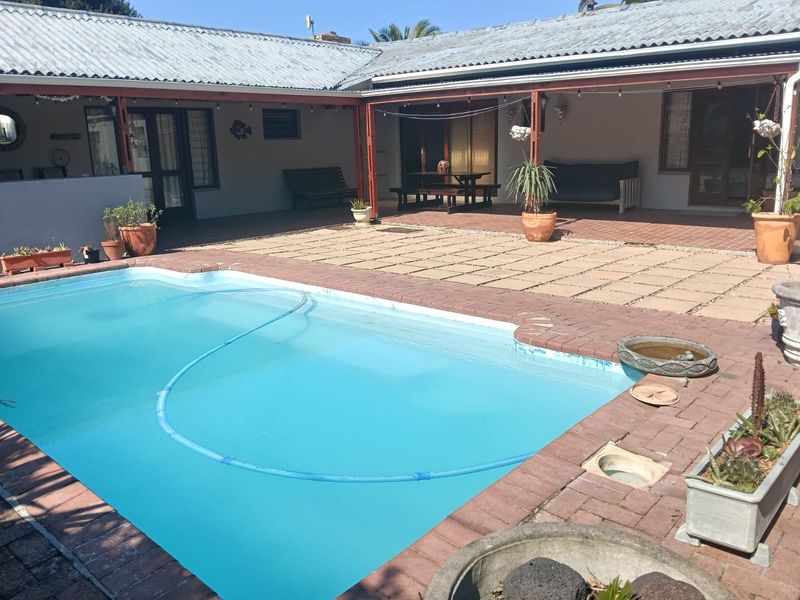 Outdoor entertainment area featuring a swimming pool, brick-paved patio, and a covered veranda attached to the main house structure.