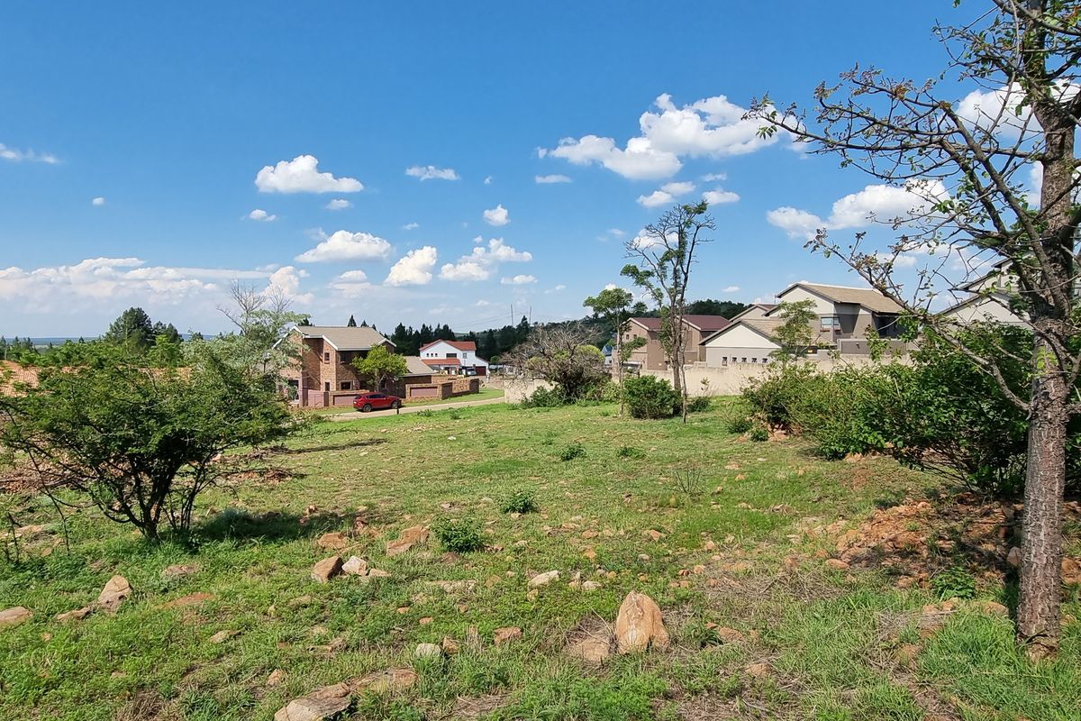 A view of an undeveloped residential plot of land situated within a suburban estate, surrounded by existing housing developments.
