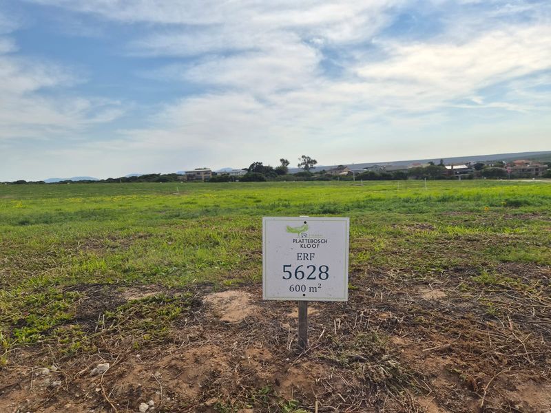 A vacant residential plot measuring 600 square meters, featuring open grass terrain and clear signage identifying the erf number.