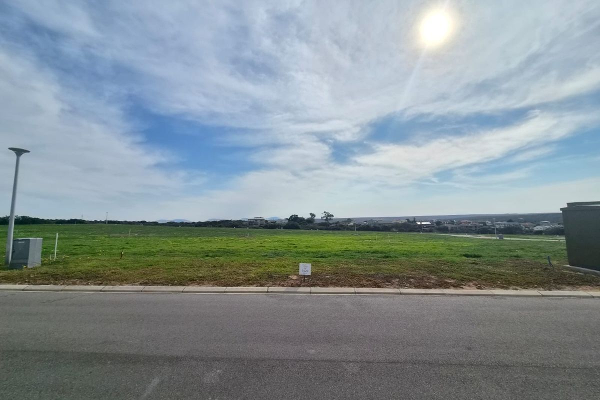 A vacant residential plot of land featuring a level grassy surface, street access, and utility connections, ready for development.