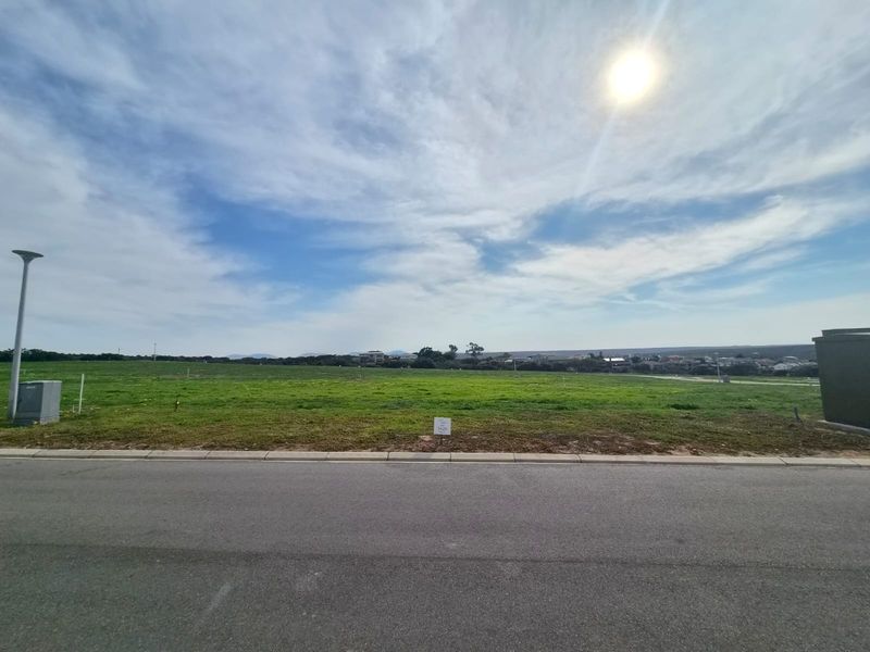 A vacant residential plot of land featuring a level grassy surface, street access, and utility connections, ready for development.