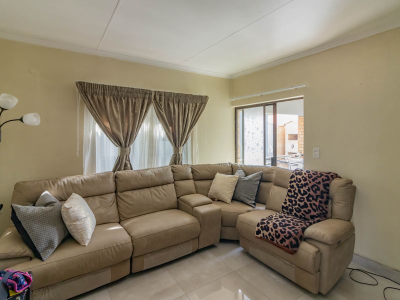 A comfortable living room featuring tiled flooring and a sliding glass door providing access to the exterior.