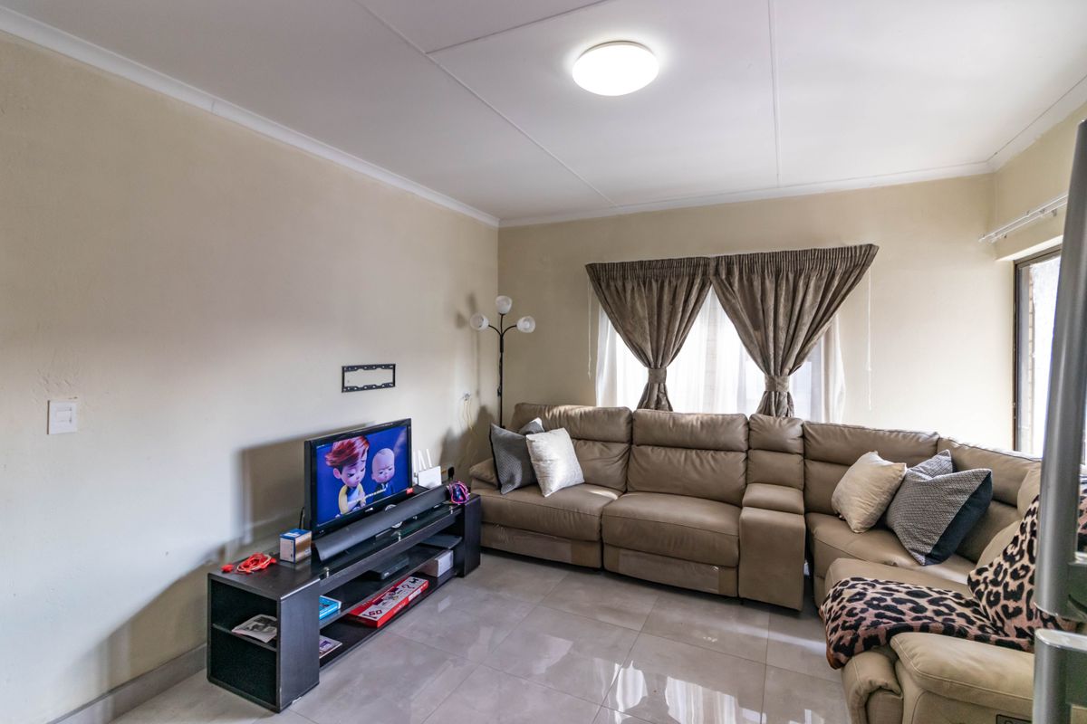 A comfortable living room featuring neutral wall tones, large format floor tiles, and a coved ceiling with a central light fixture.