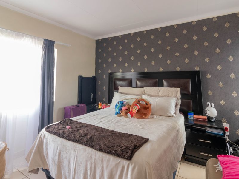 A bedroom featuring a dark patterned accent wall, tiled flooring, and a window with curtains.