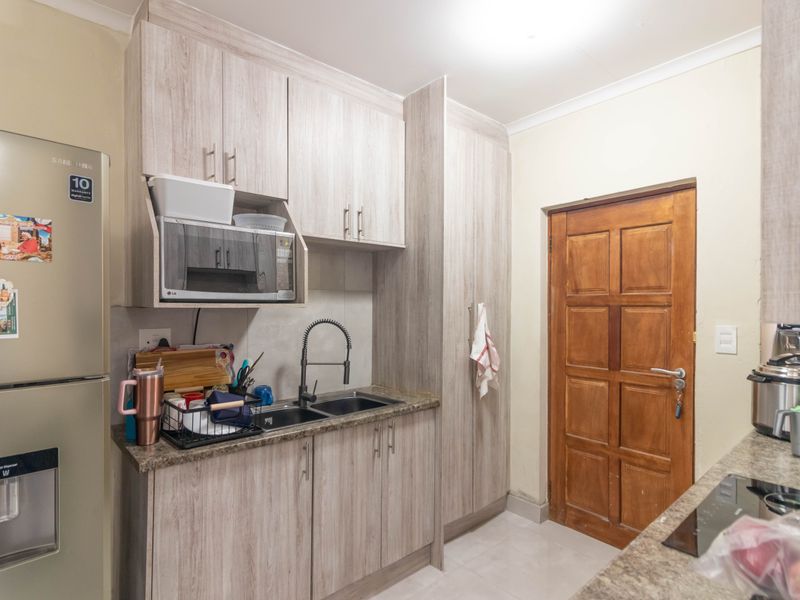 A functional kitchen featuring light wood-grain cabinetry, granite countertops, a double sink with a modern faucet, and a built-in microwave.