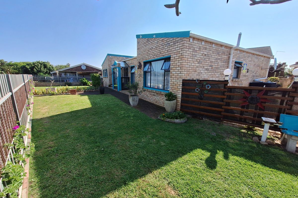 A rear view of a face brick house featuring a well-maintained lawn, paved walkway, and timber privacy screening.