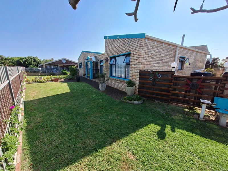 A rear view of a face brick house featuring a well-maintained lawn, paved walkway, and timber privacy screening.