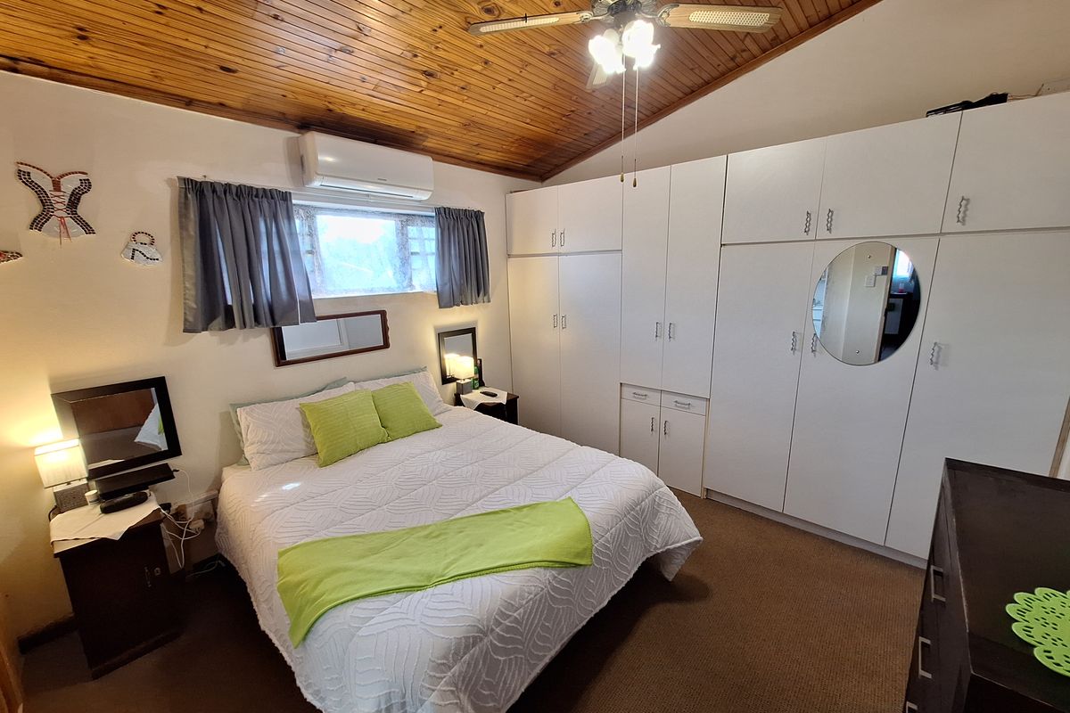 A bedroom featuring a timber-clad vaulted ceiling, ceiling fan, split-system air conditioning, and extensive built-in wardrobe storage.
