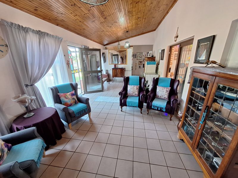 A spacious living area featuring a vaulted timber-clad ceiling, ceramic tiled flooring, and direct access to the exterior through a sliding glass door.
