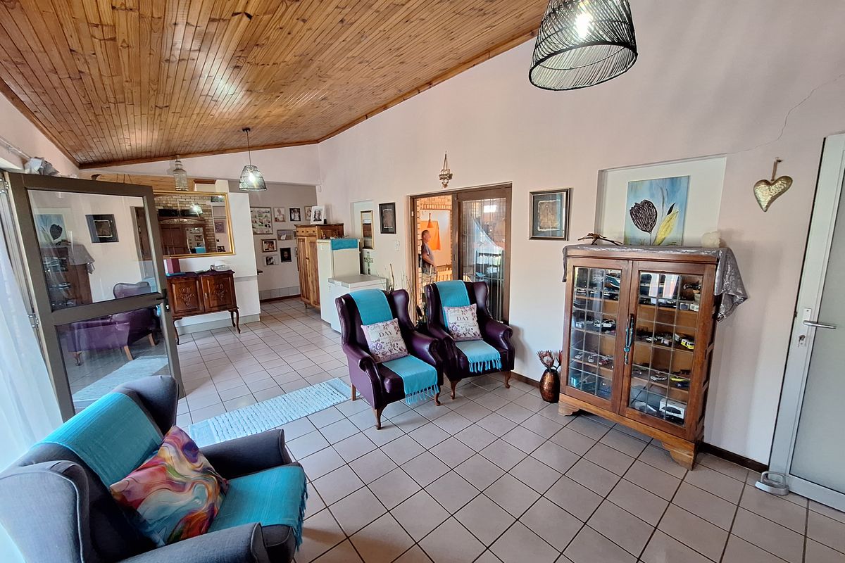Spacious living area featuring a vaulted timber-clad ceiling, ceramic tiled flooring, and a recessed wall niche, offering a versatile layout for relaxation.